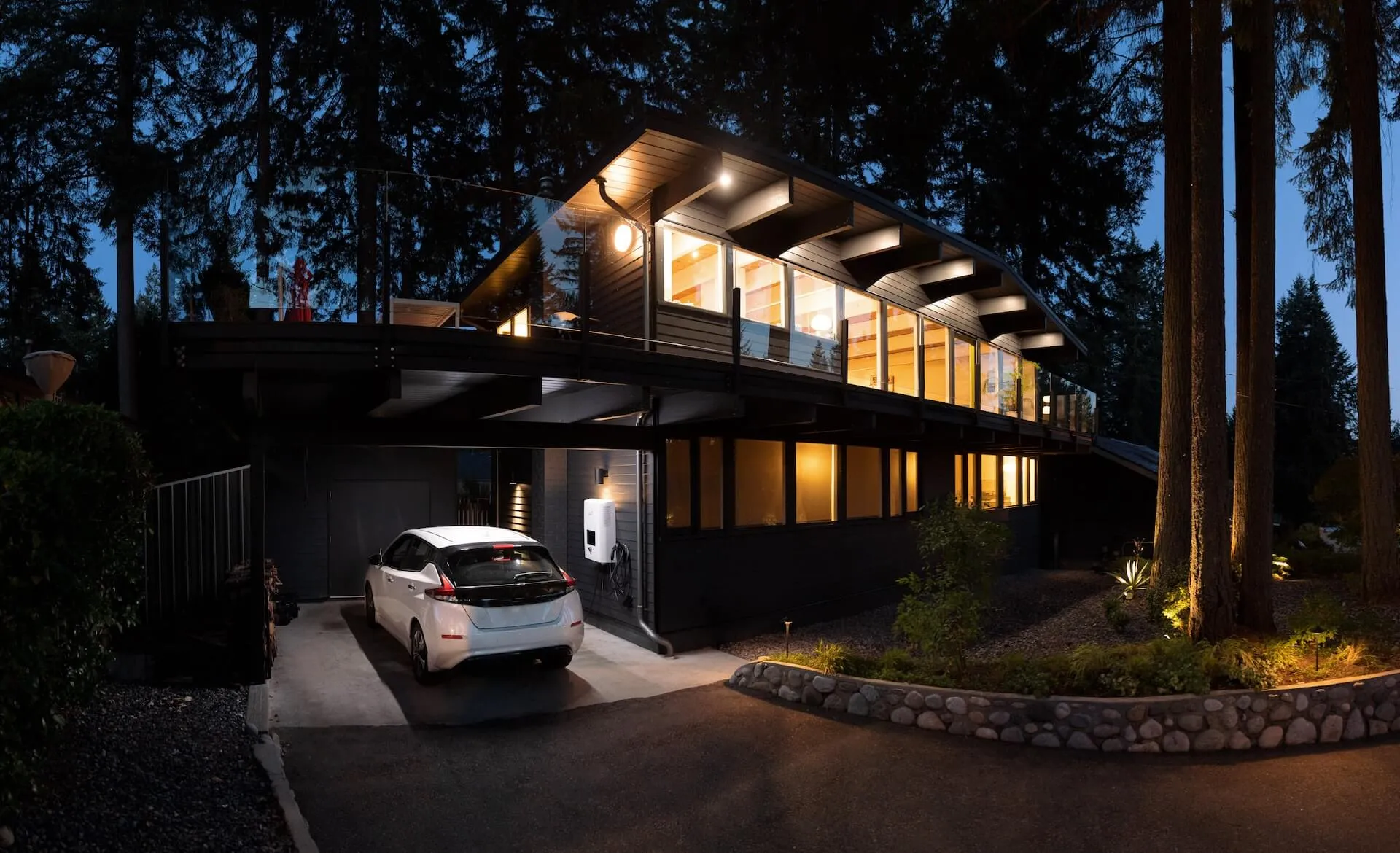 An electric vehicle charging beside a warmly lit home